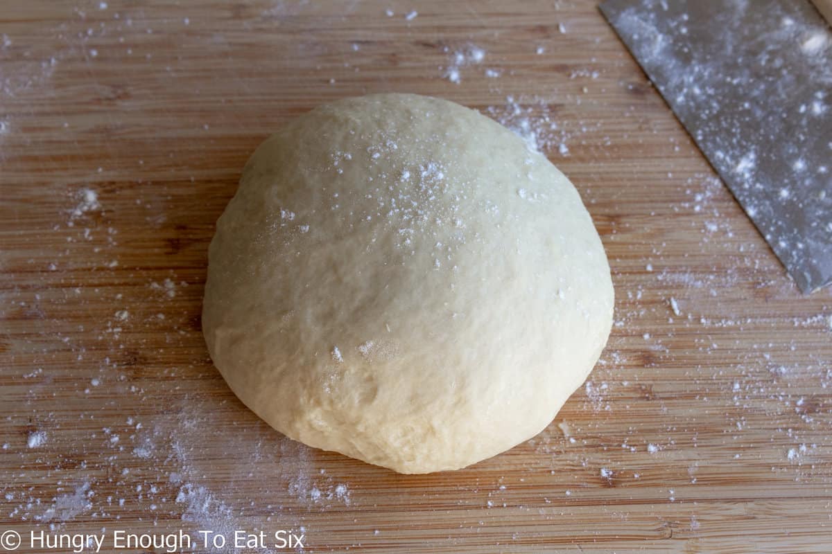Round of bread dough on a flour dusted cutting board.