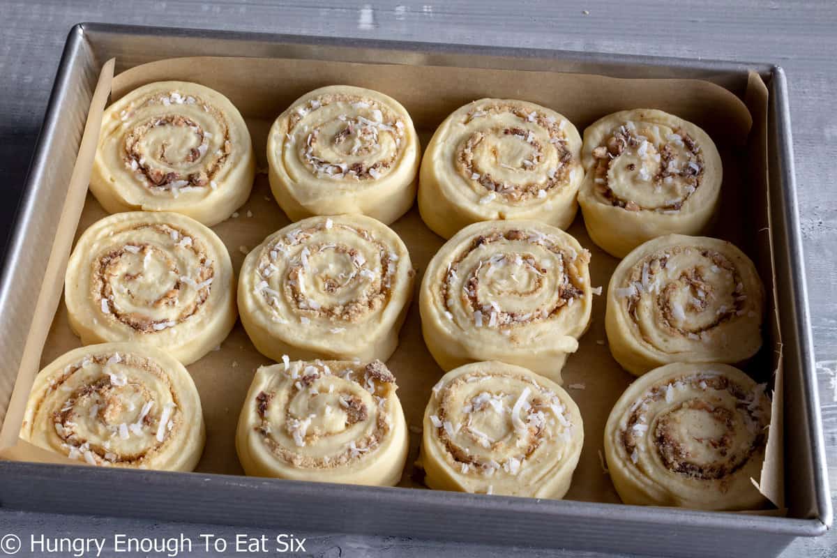 Unbaked filled sweet rolls in a baking pan.
