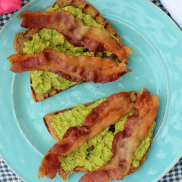 Two slices of avocado toast with bacon on a plate