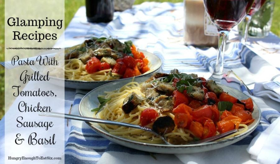 Outdoor table with gray plate of pasta and tomatoes.