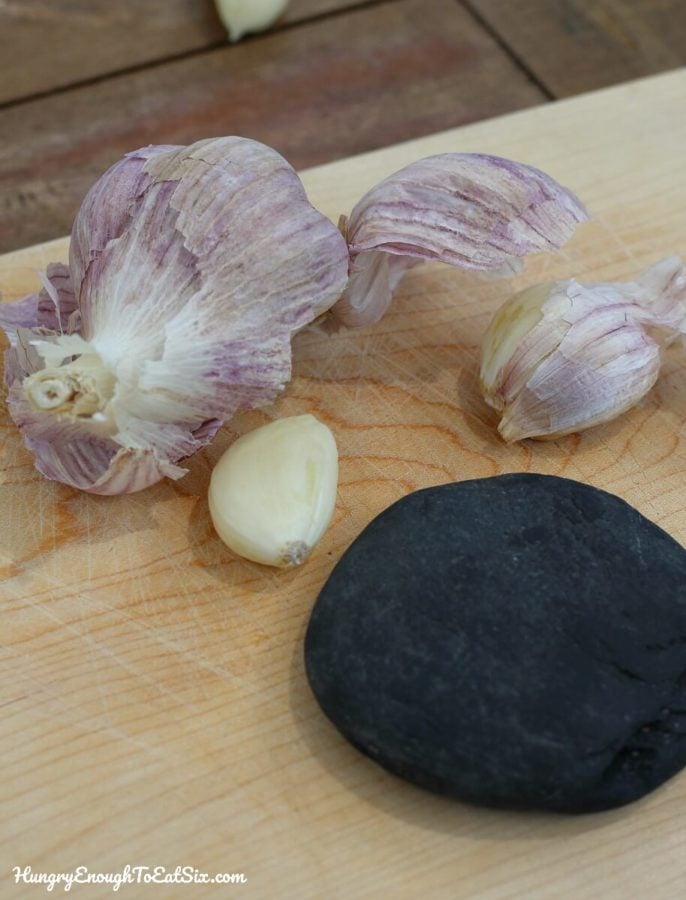 Garlic cloves next to a round flat rock