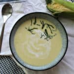 Creamy corn soup with cream swirl and herbs.