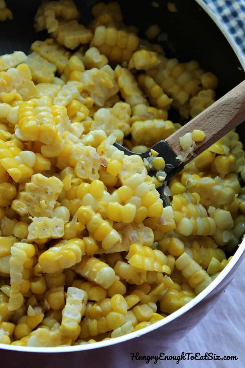Corn kernels in a pot with a spatula.