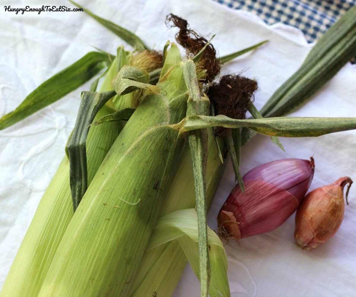 Image of ears of corn and shallots on a white tablecloth