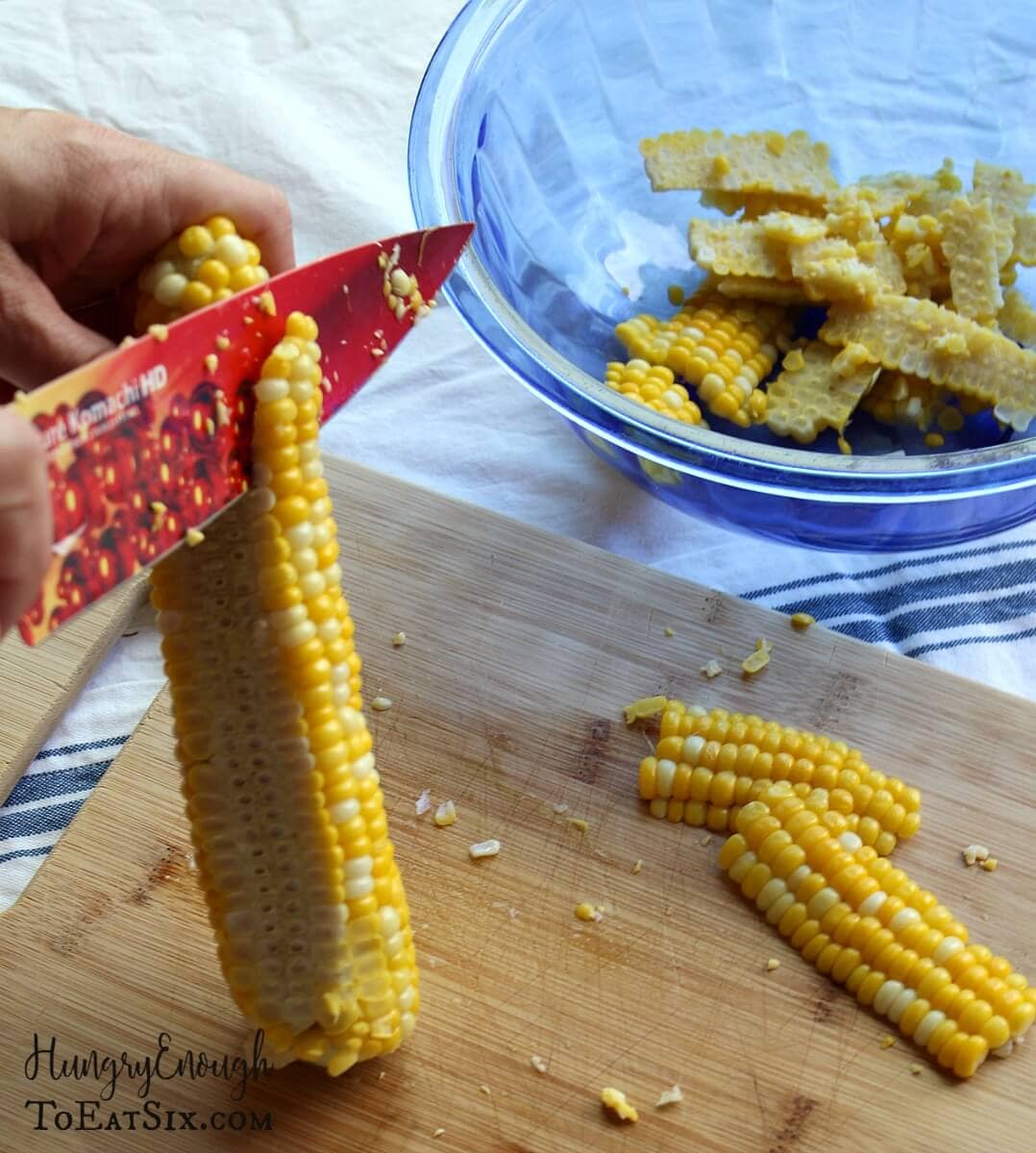 Image of a knife slicing kernels of a cob of sweet corn