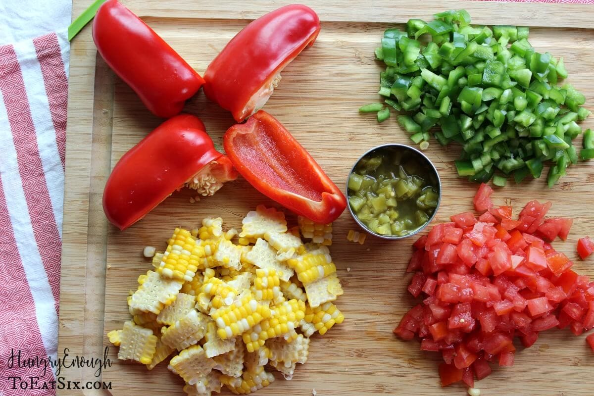 Image of chopped peppers, corn, tomatoes and chiles on a cutting board