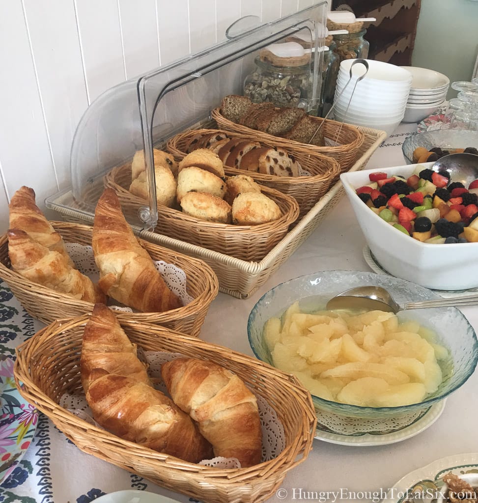 Brunch table with baskets of pastries and fruit in bowls. 