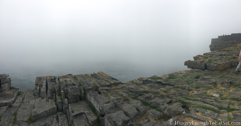 Edge of rock ledge with ocean and fog below. 