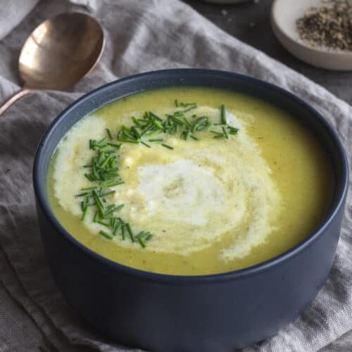 Bowl of yellowish soup with diced chives and cream