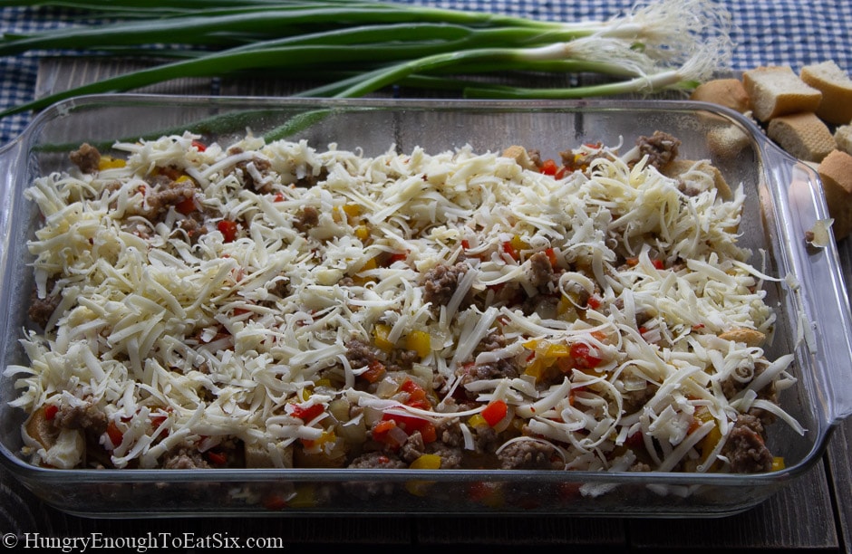 Image of diced veggies, bread cubes, sausage and cheese in a casserole dish.