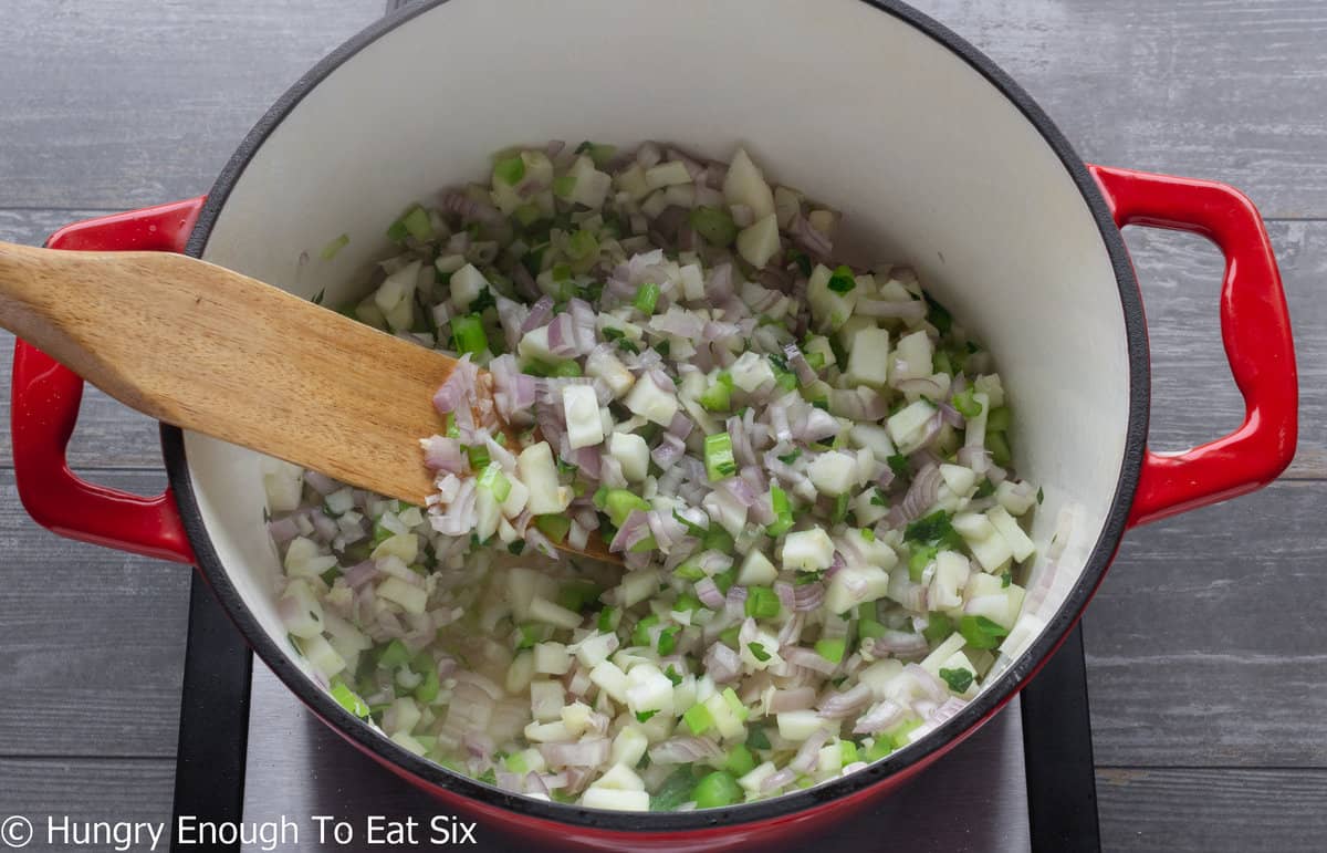Diced shallows, celery and apple in pot with wooden spoon.