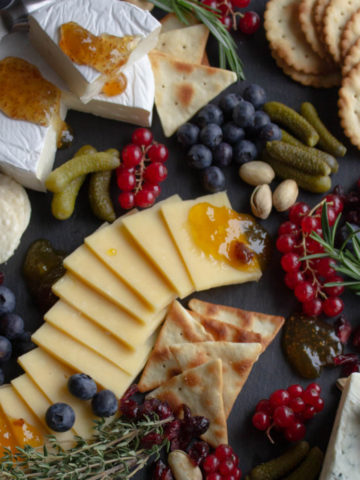 Berries, cheeses, crackers arranged on a black board