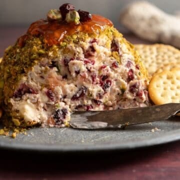 Cheese ball with pistachios and cranberries and crackers.