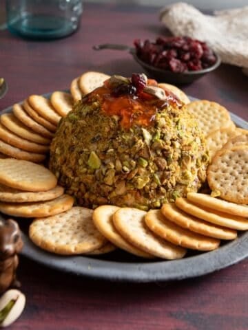 Plate with crackers around a cranberry pistachio cheese ball.