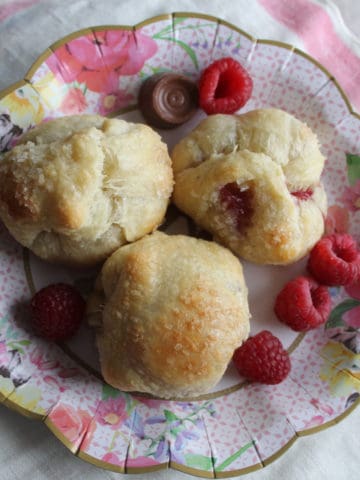 Raspberries surrounding three baked puff pastry pockets.