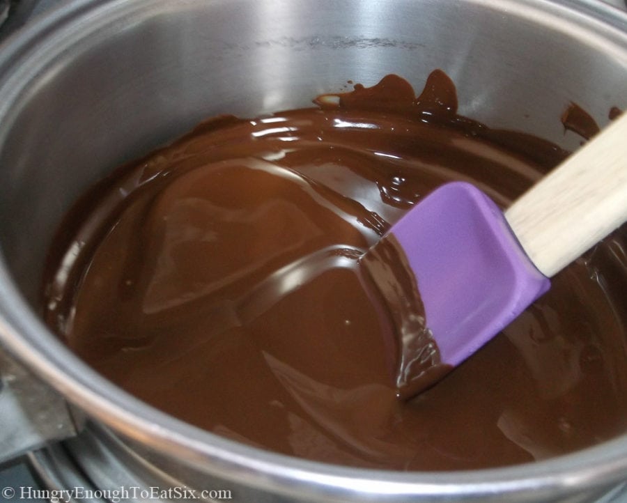 Metal pan with melted chocolate and a spatula.