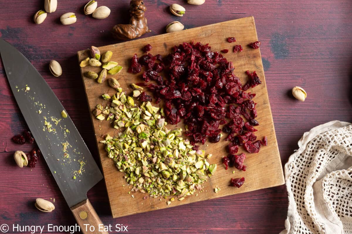 Cutting board with chopped pistachios and dried cranberries.
