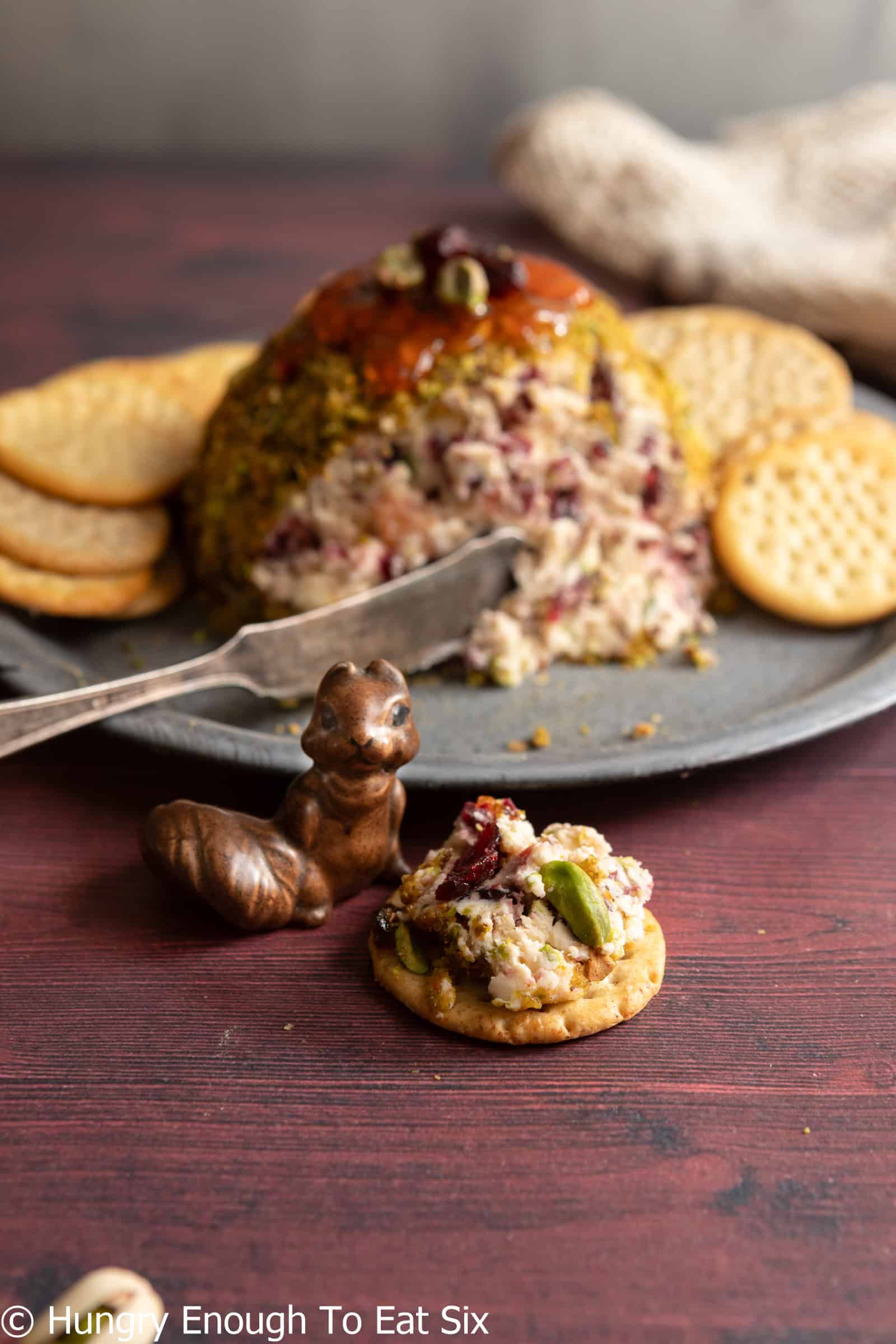 Cranberry pistachio cheese ball with some spread on a cracker.