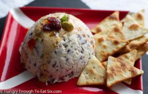 White goat cheese ball with pepper jelly and crackers.