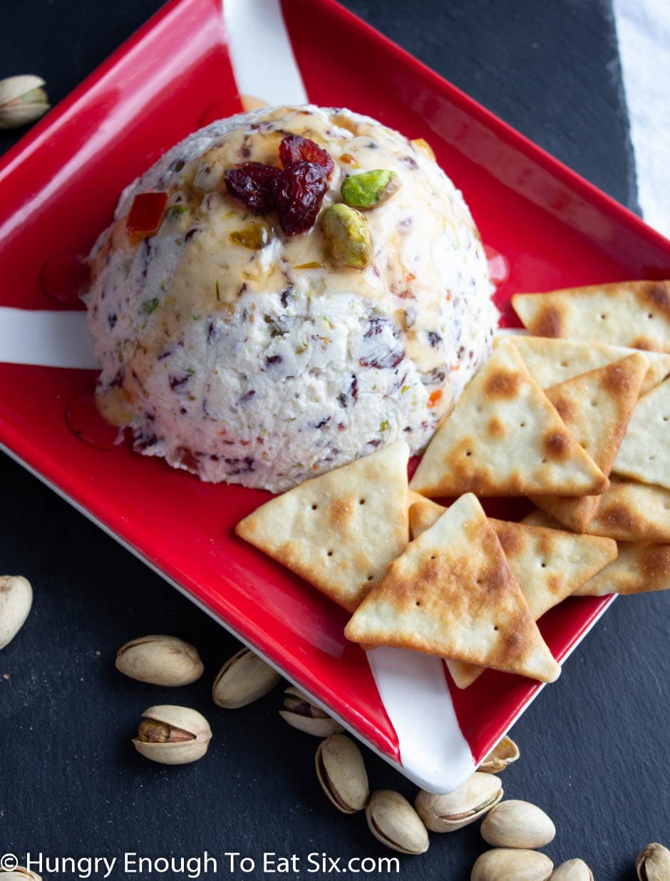 Red plate with goat cheese ball and triangle crackers.
