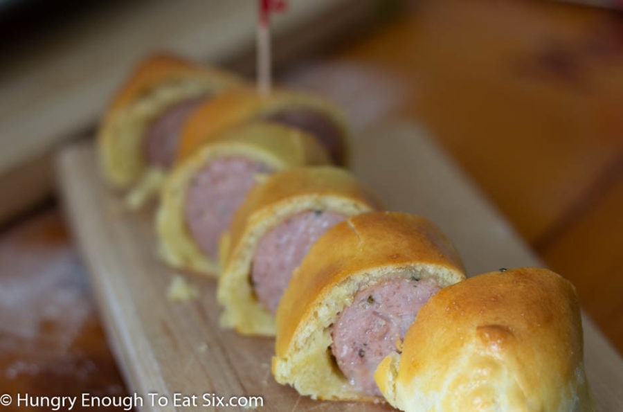 Sliced pastry wrapped sausage on a cutting board