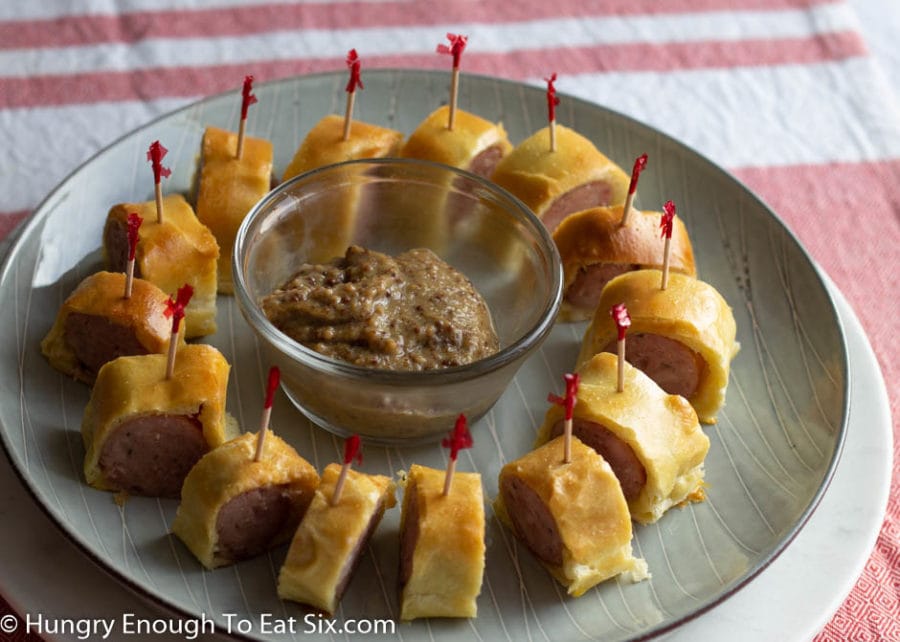 Ring of sausage bites with toothpicks on a plate with dip in the center