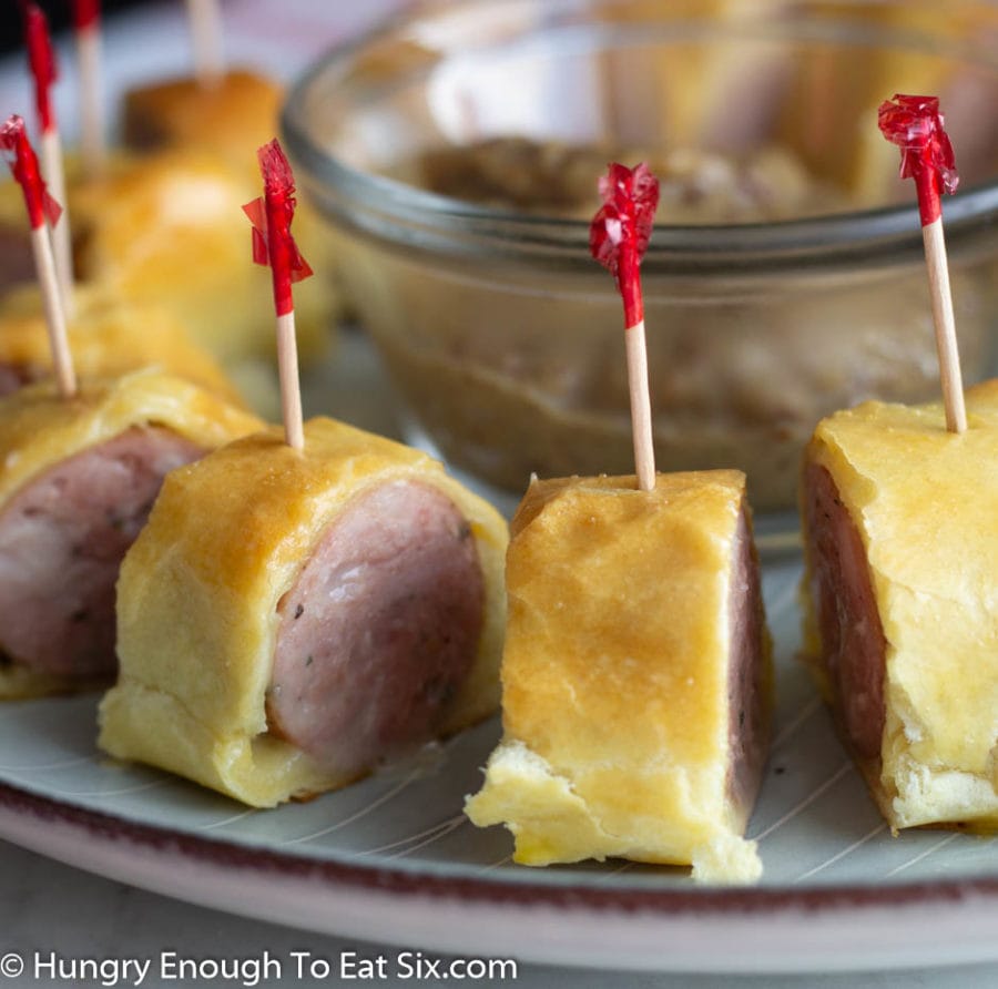 Slices of sausage wrapped in pastry with red topped toothpicks