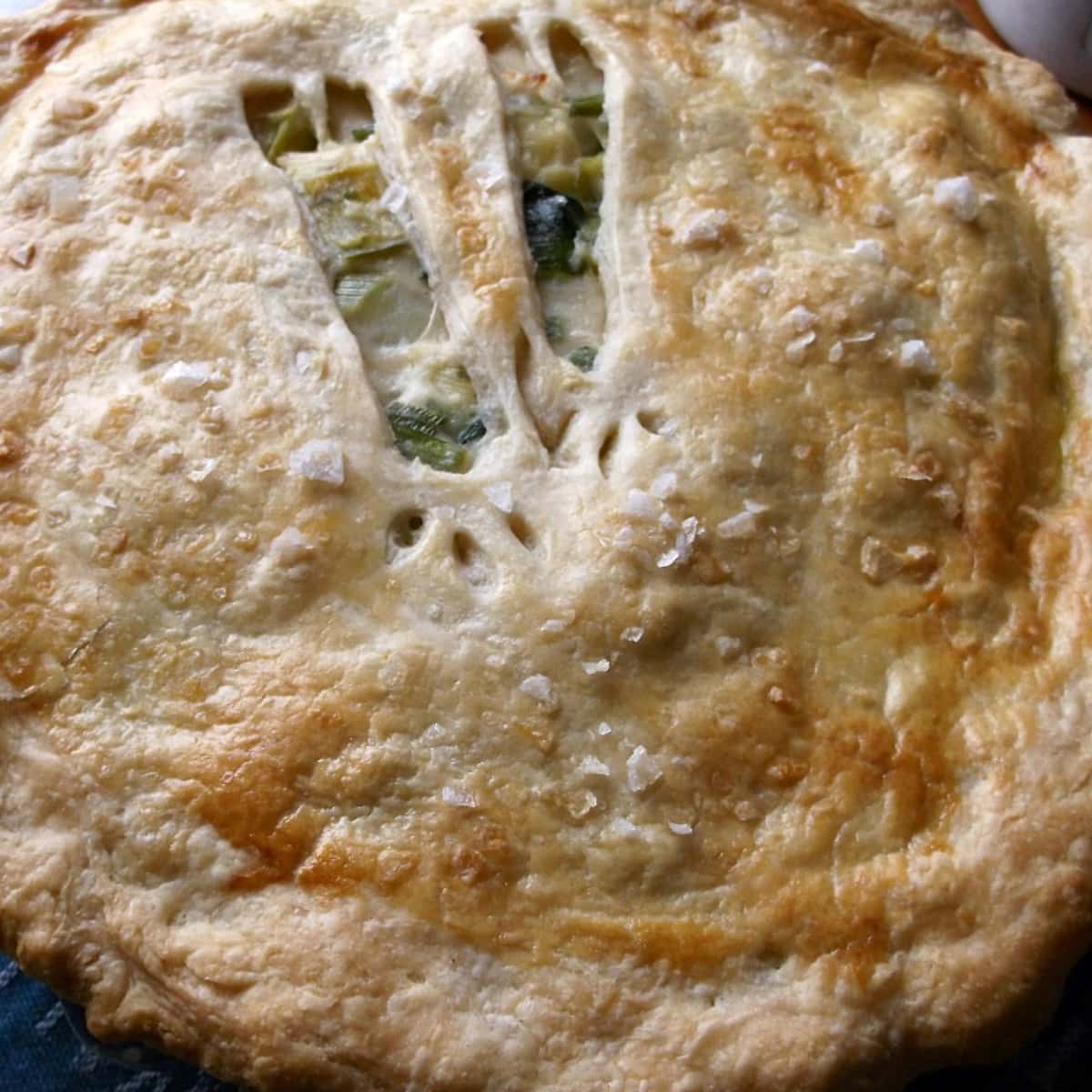 Whole pie with browned crust and leek-shaped cutouts in top