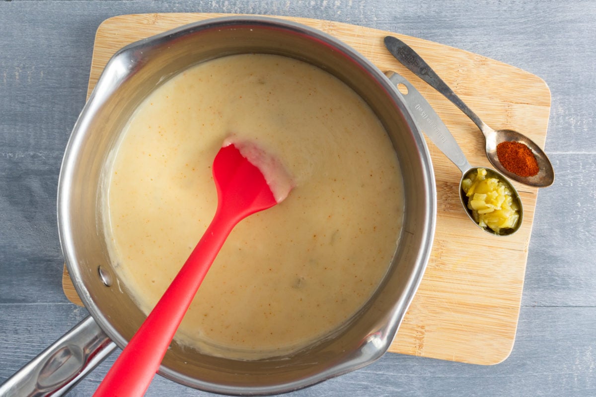 Cheese sauce in saucepan with red spatula