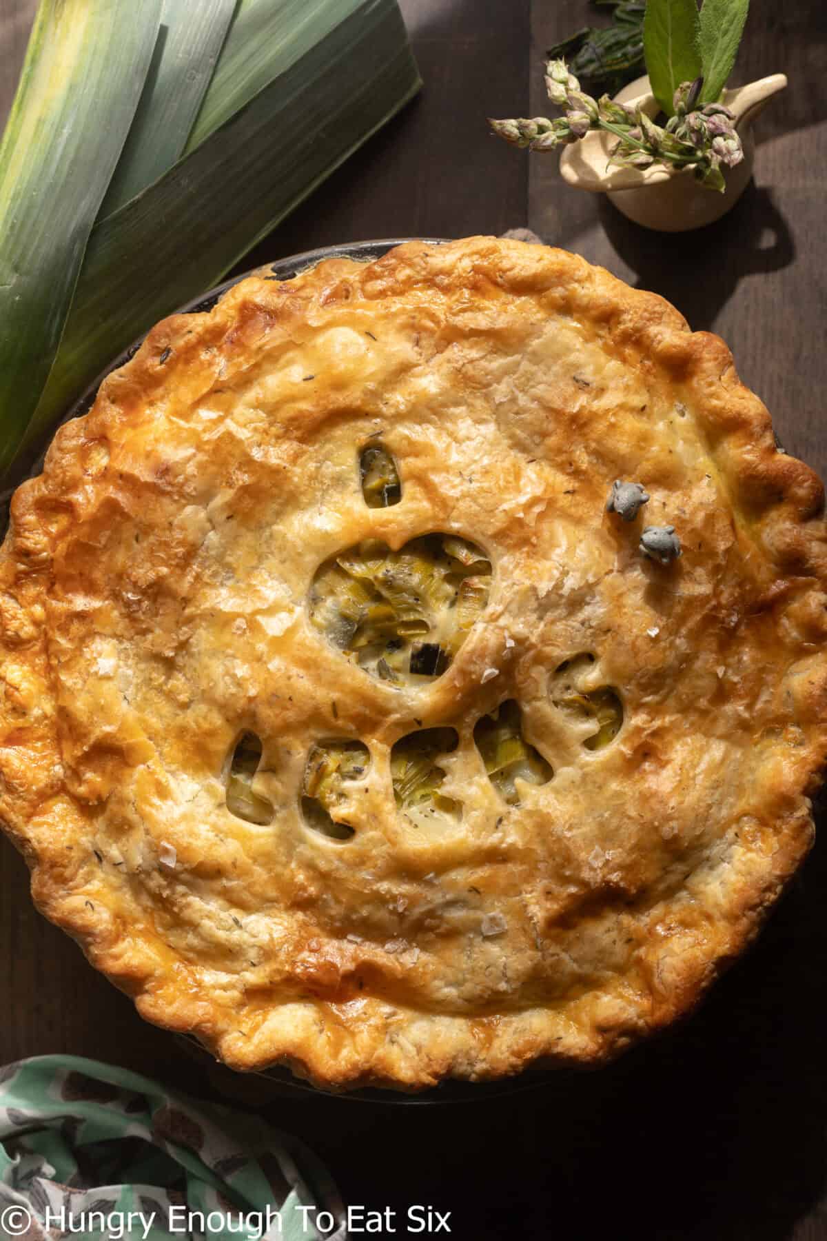 Round baked leek and potato pie with letter cutouts in crust.