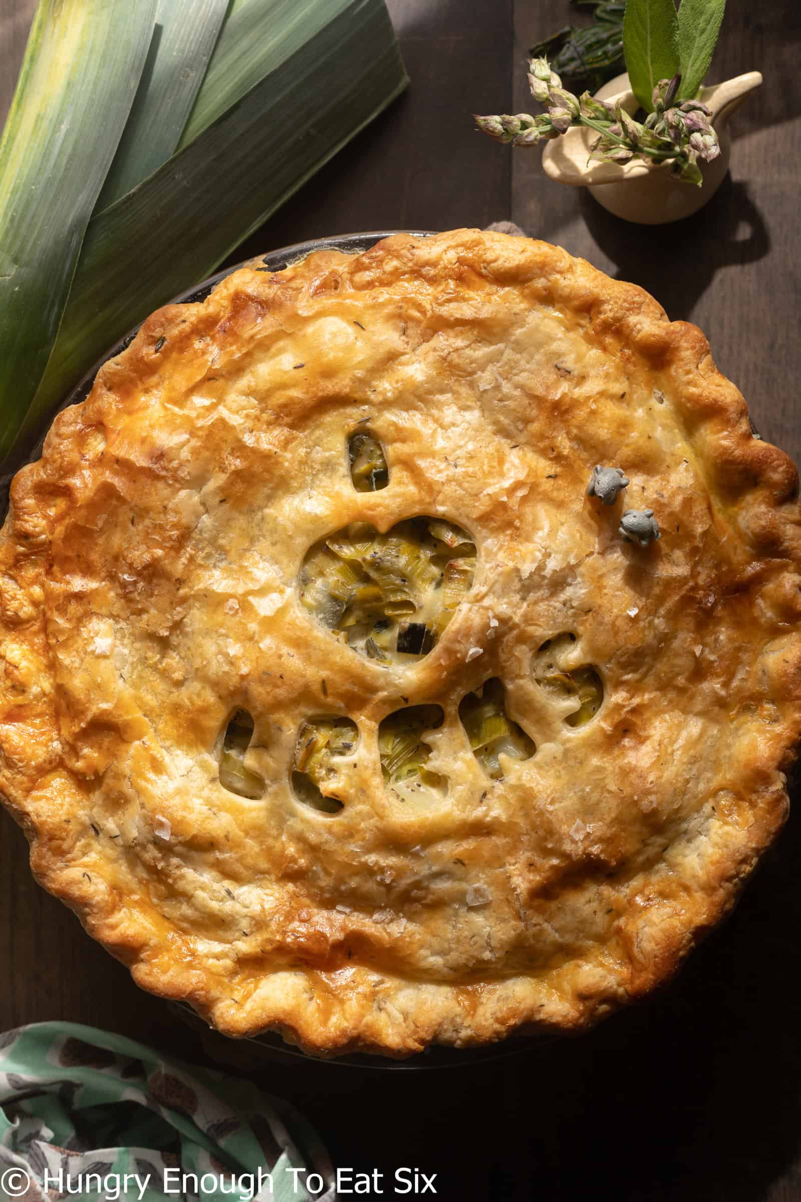 Round baked leek and potato pie with letter cutouts in crust.