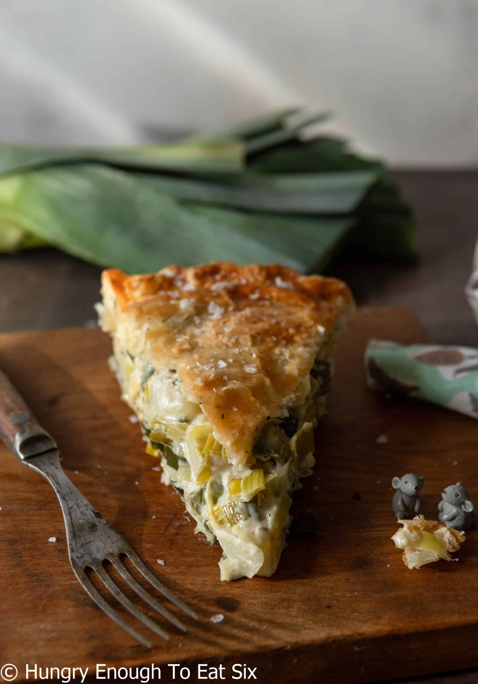 Slice of leek and potato pie with flaky crust resting on a board.
