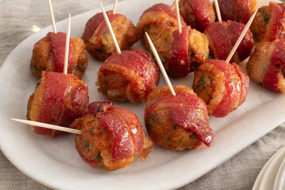 Bacon wrapped meatballs with toothpicks on white plate