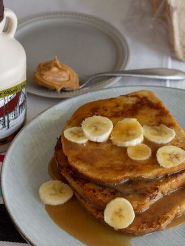 Plate of French toast with bananas and syrups.
