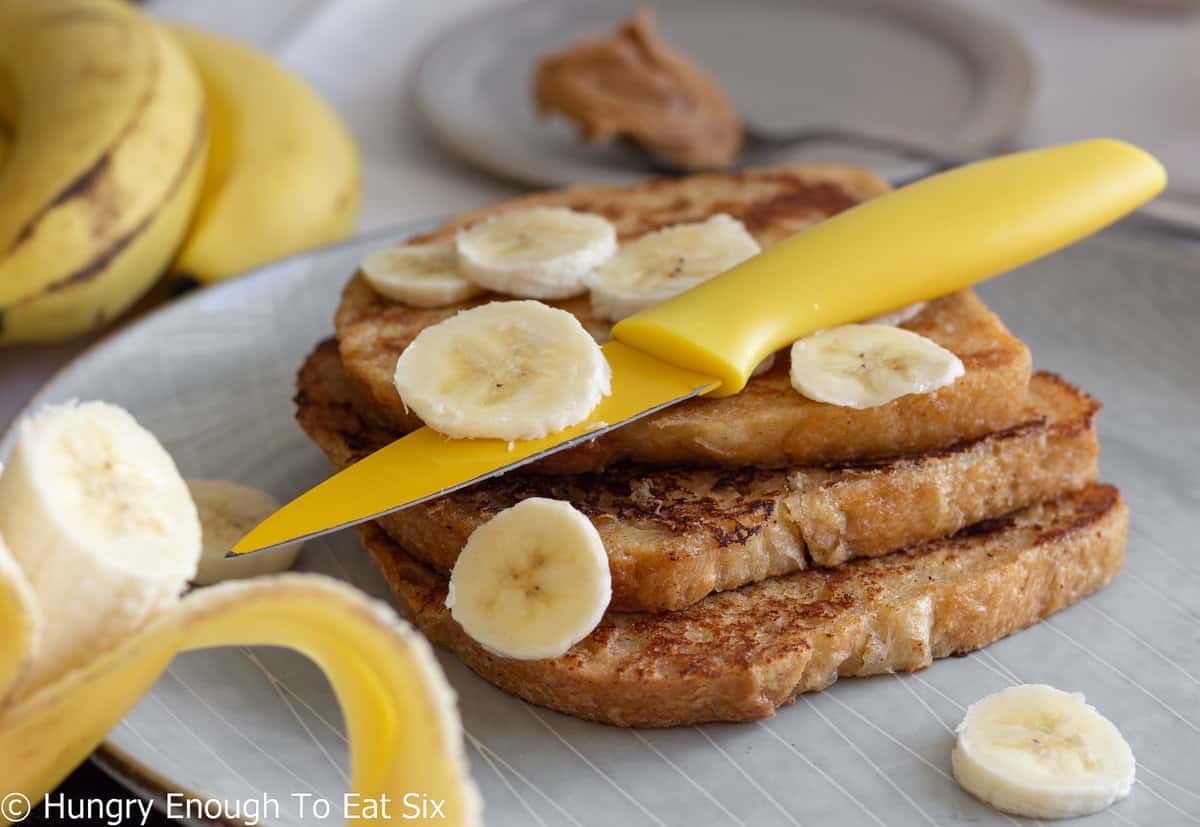 French toast with bananas and yellow knife.