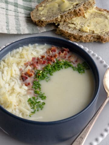 Creamy soup in a bowl with cheese and toppings.