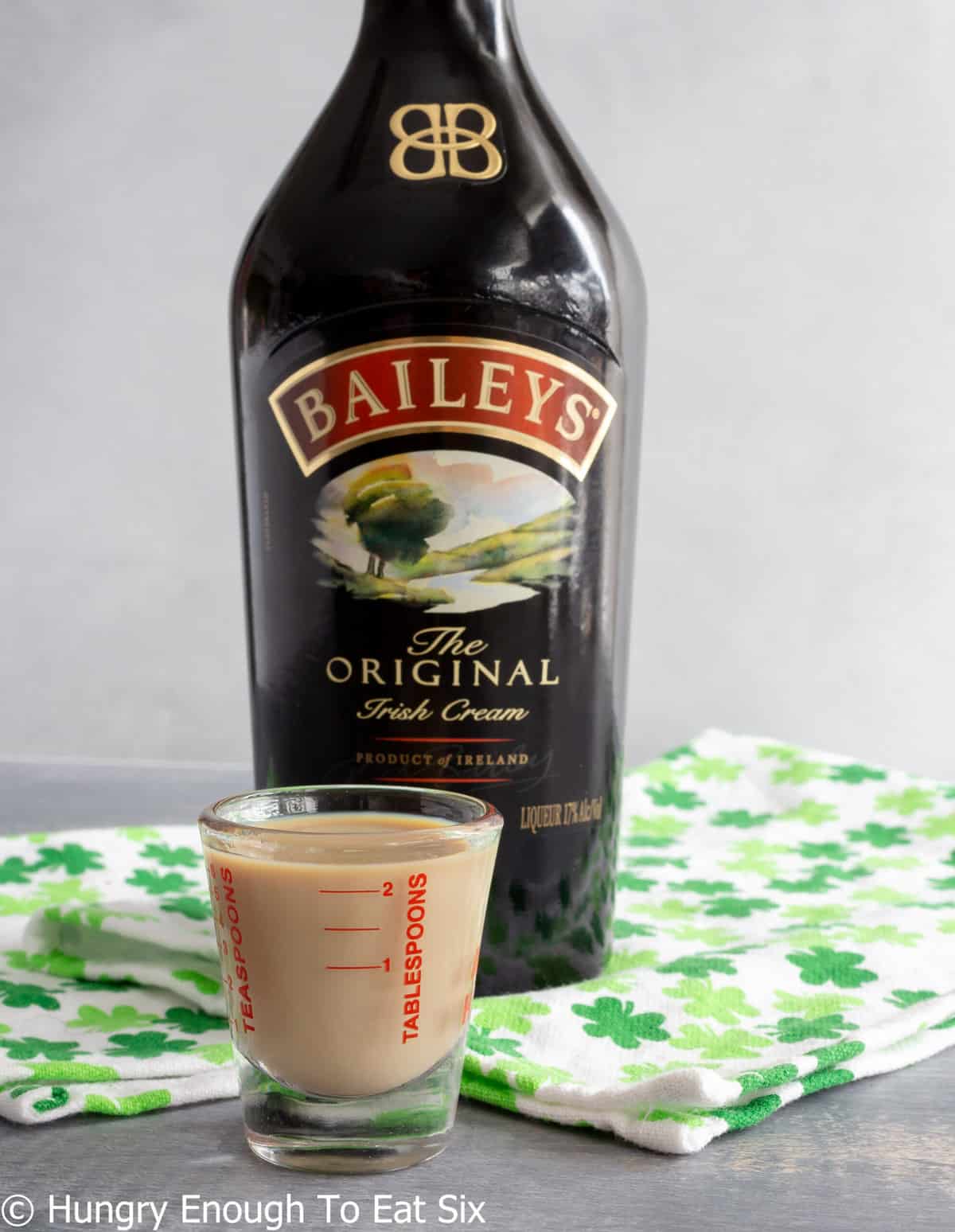 Bottle of Baileys Irish cream with shot glass full of liqueur.