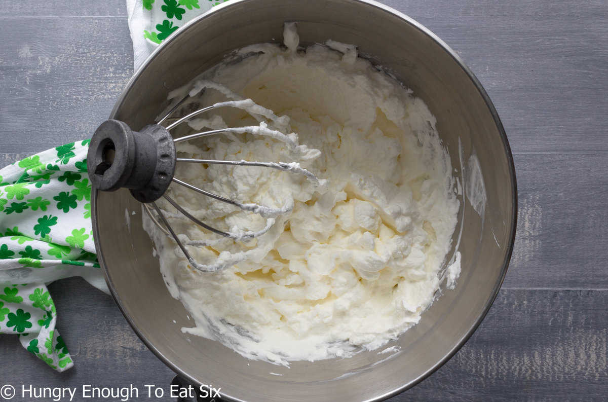 Whipped cream in a mixing bowl with whisk attachment.