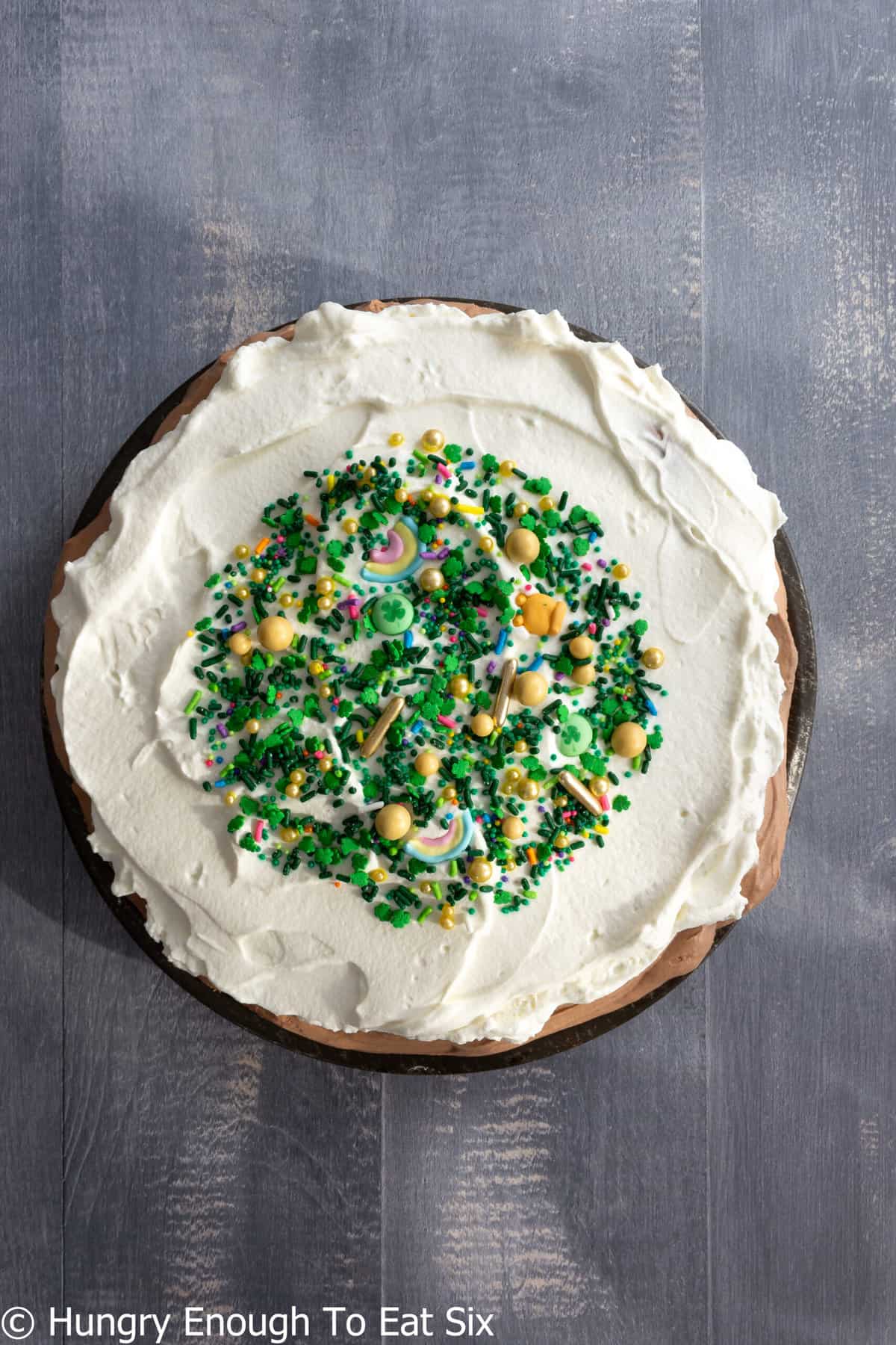 Round cream-topped pie with center of green and yellow sprinkles.