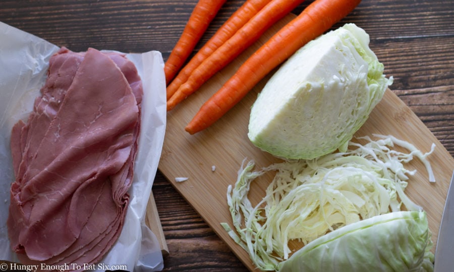 Carrots and a quarter of a cabbage next to slices of corned beef.