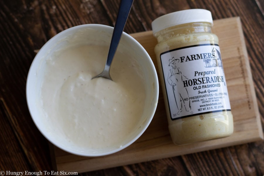 A jar of horseradish next to a bowl of horseradish mayonnaise.