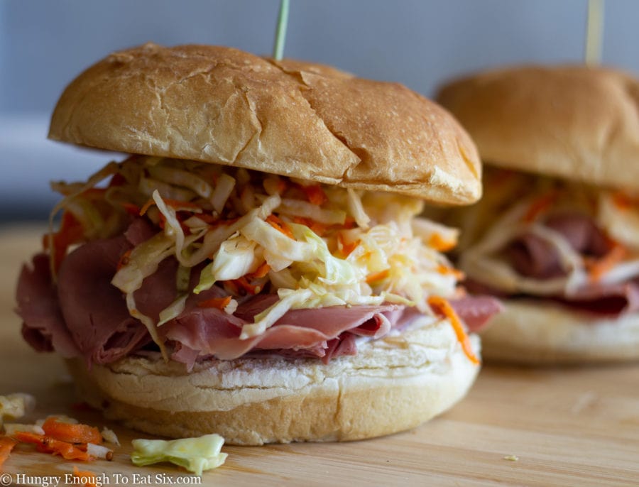 Closeup of a corned beef sandwich on a potato roll with slaw.