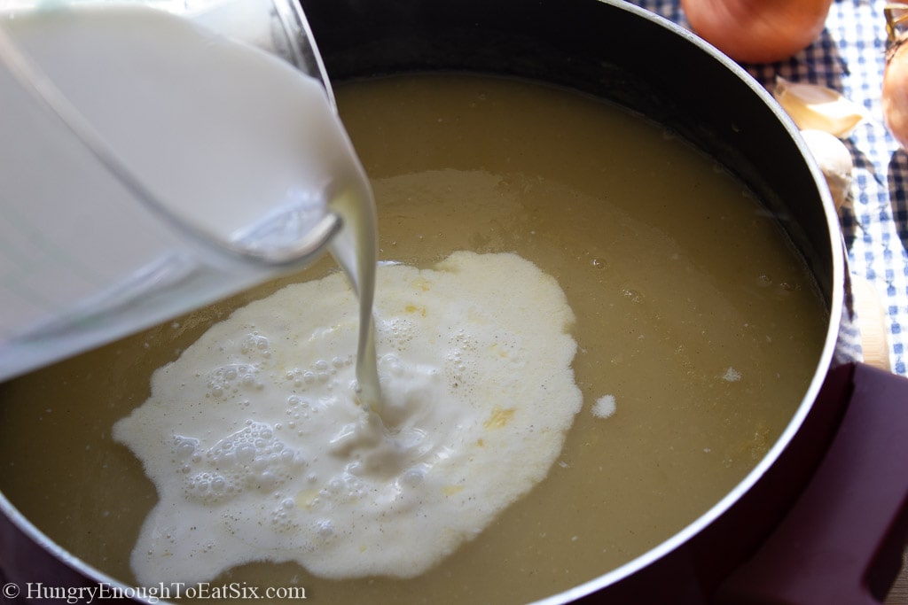Cream pouring into a pan of soup