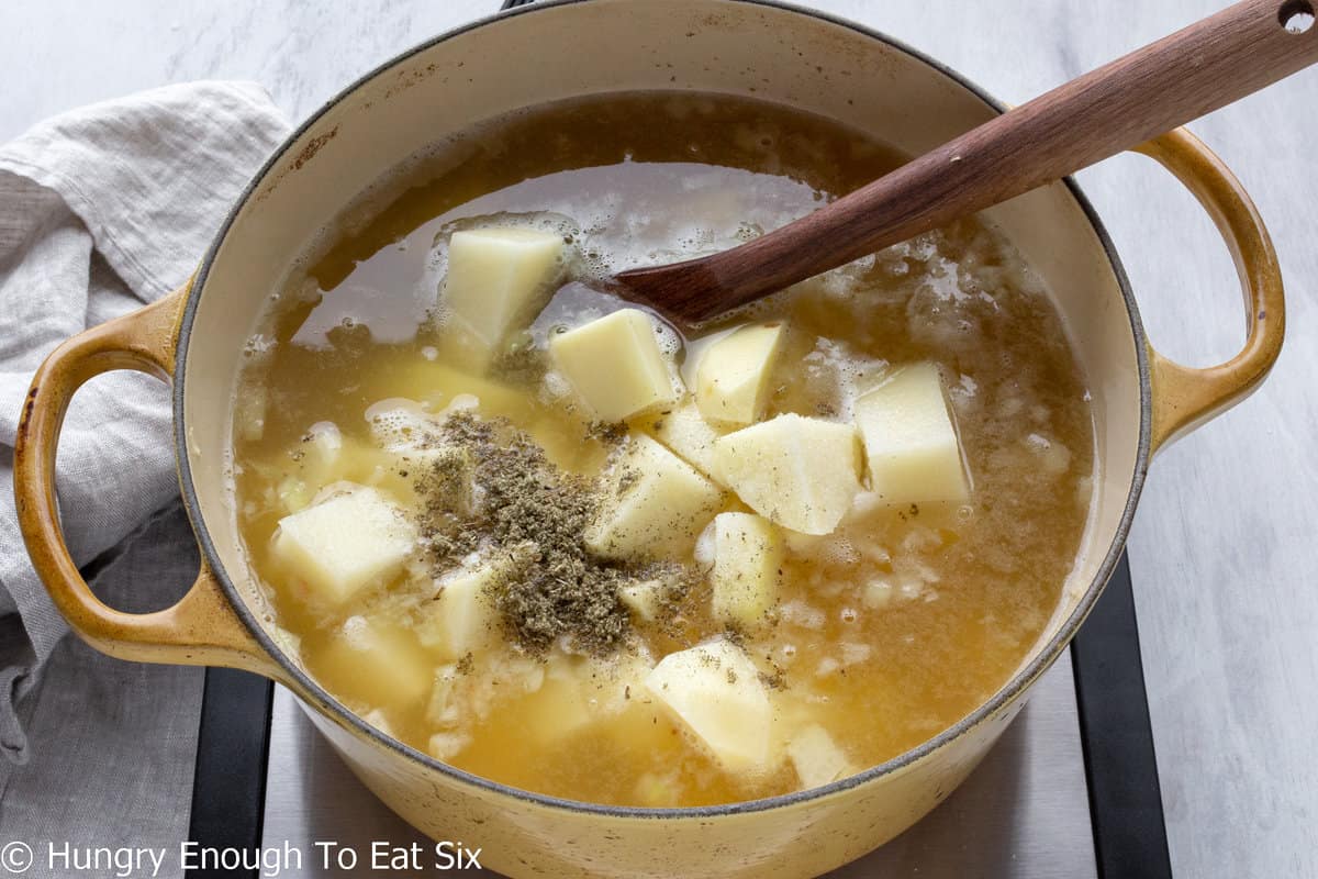 Yellow pot with broth and cubed potatoes.