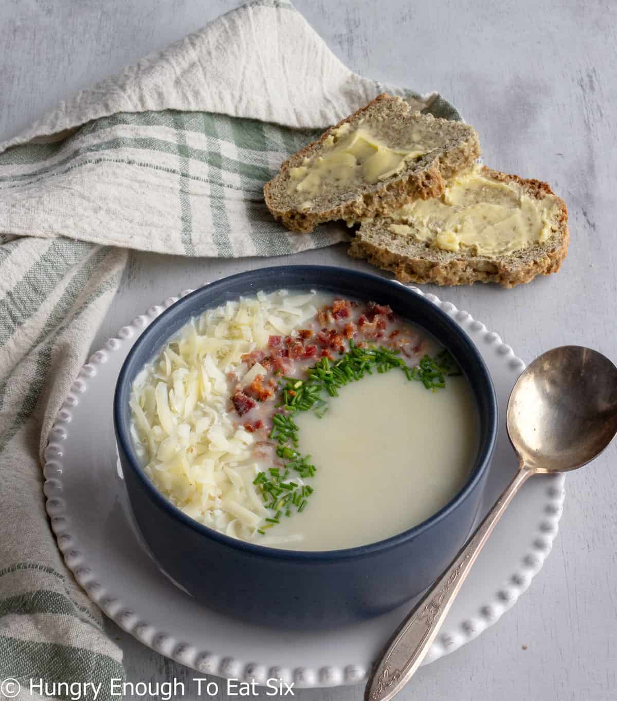 Bowl of soup with buttered bread and spoon. 