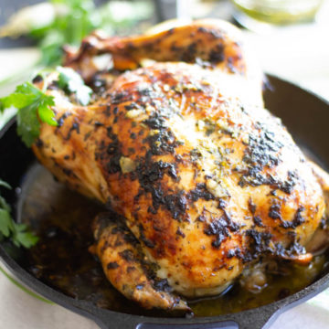 Roast chicken in a cast iron pan with parsley leaves