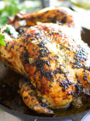 Roast chicken in a cast iron pan with parsley leaves