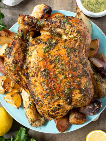 Herb-coated roast chicken on a blue plate.
