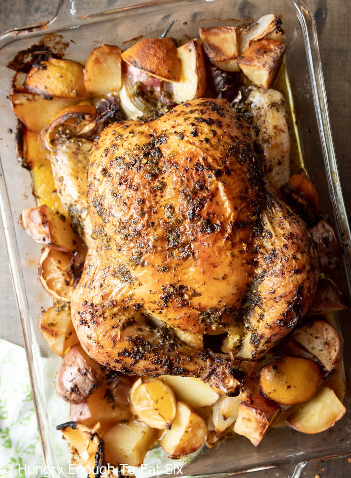Browned, roasted chicken in a baking dish with potatoes. 