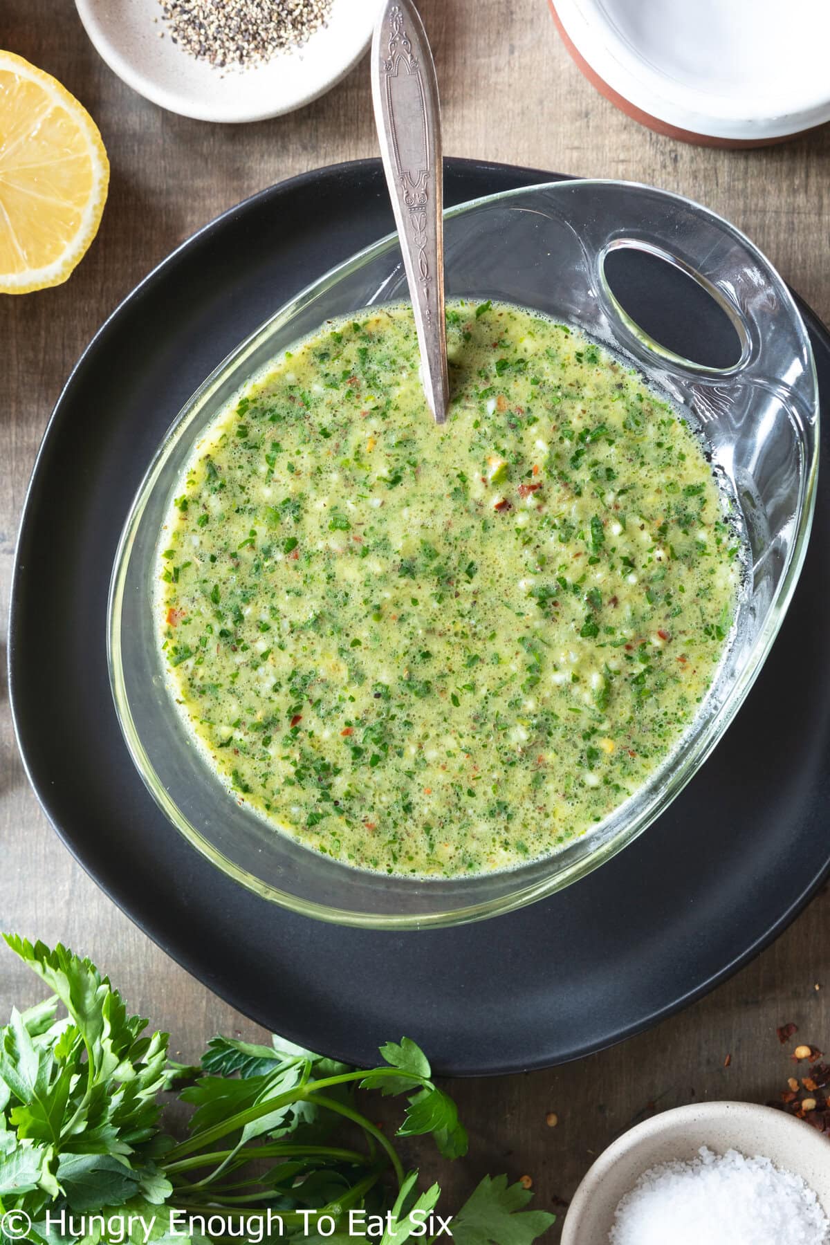 Bowl of green herb chimichurri sauce with spoon.